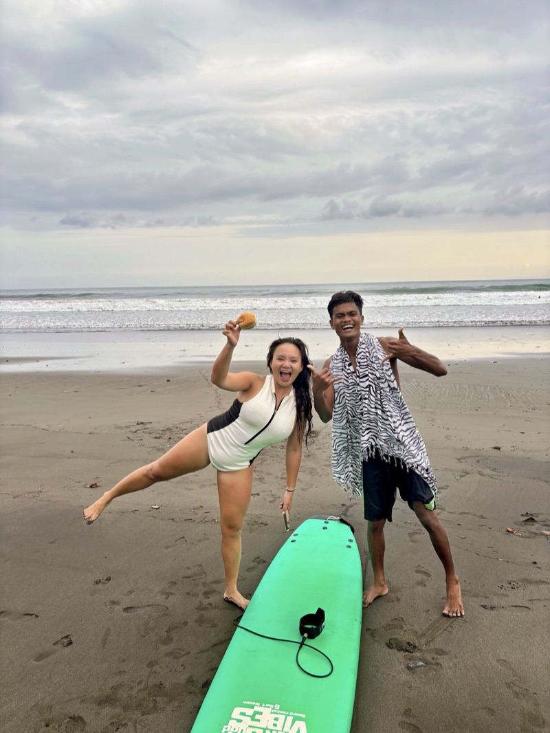 Two guests on the beach in Medewi with a softboard and a towel before a surf lesson