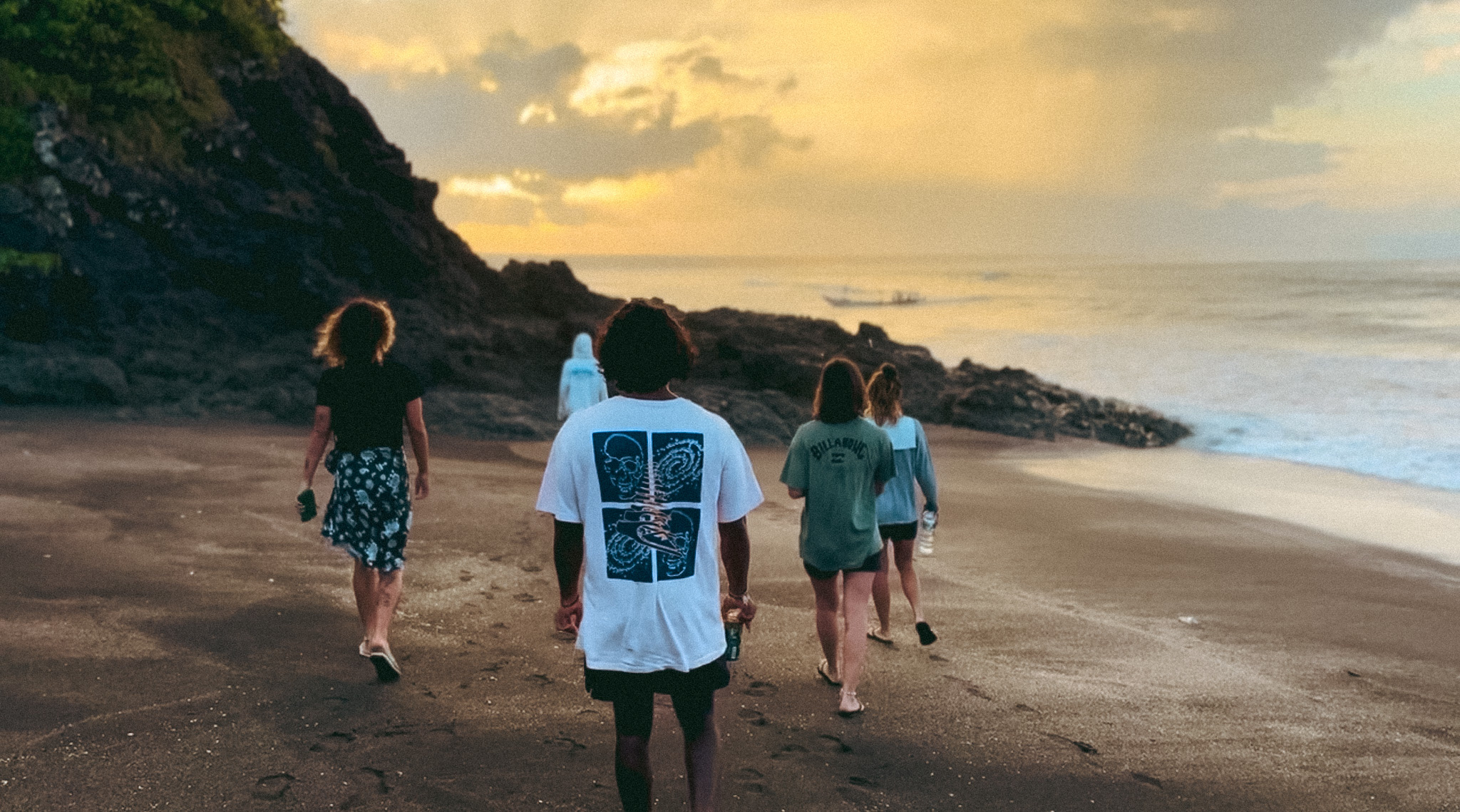 Guests walking the dark-sand beach at Grajagan at sunset