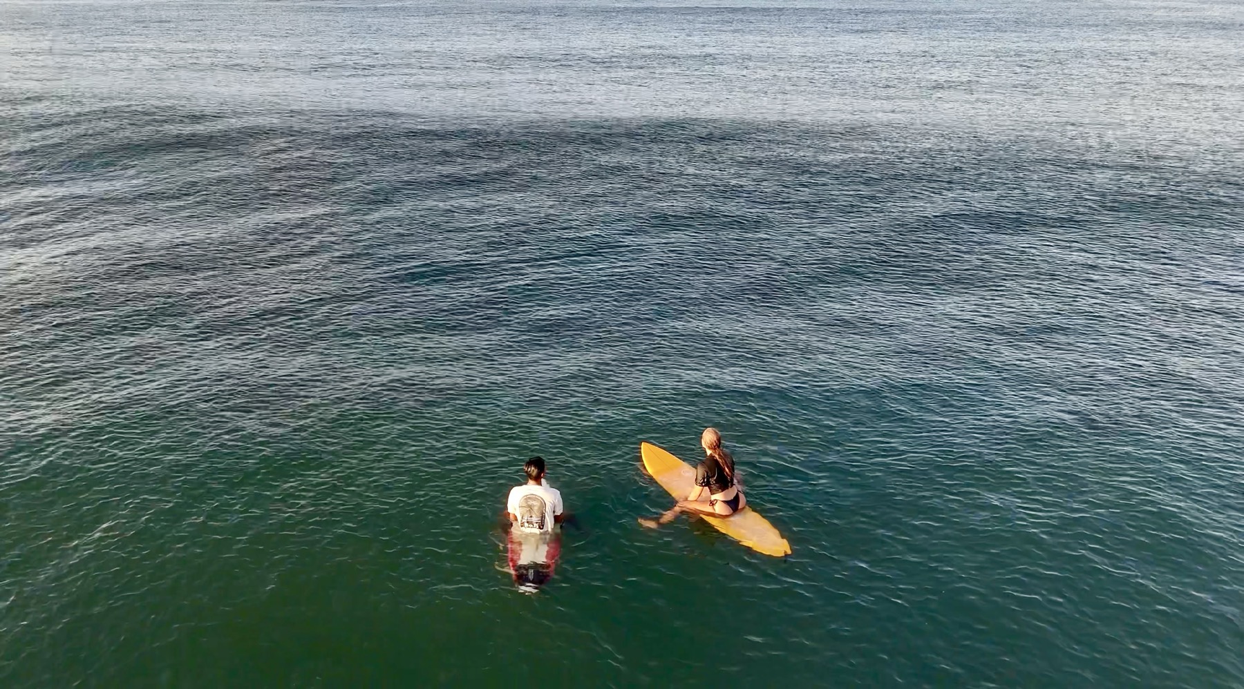 Two surfers sitting on their boards in the Medewi lineup