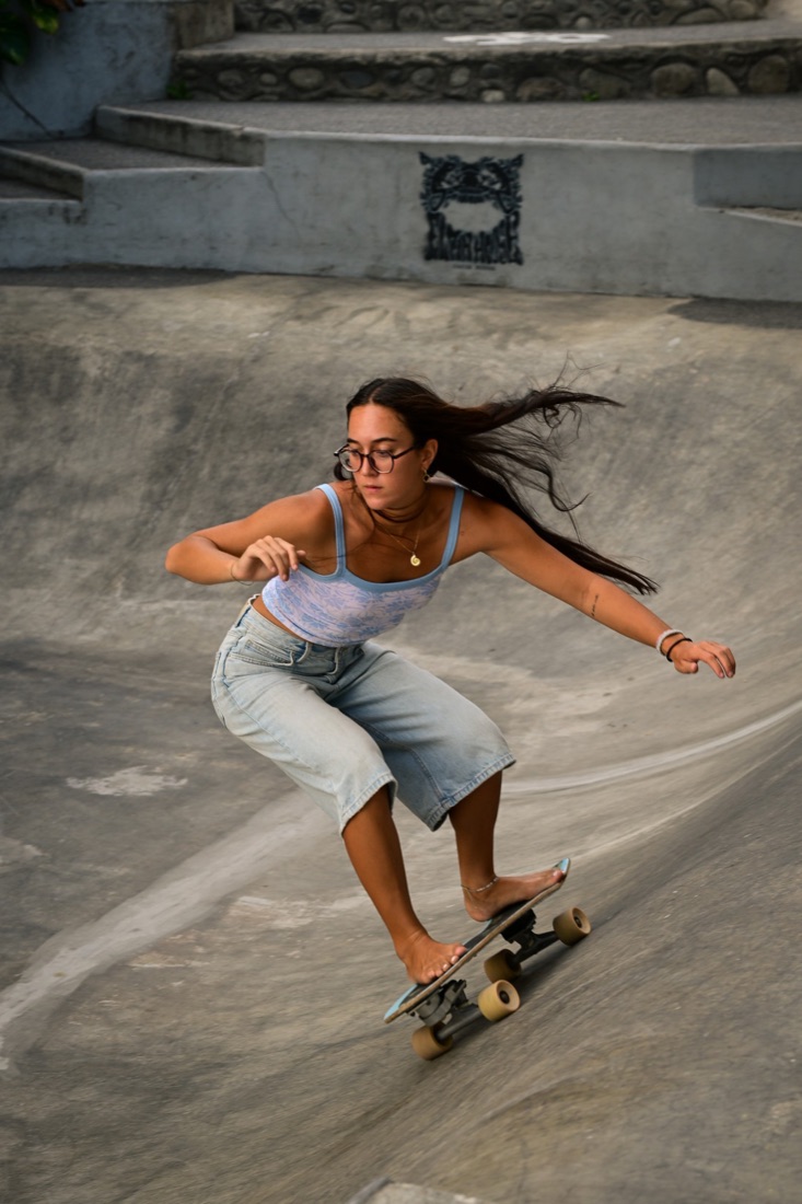 Surfer carving through a concrete bowl on a surfskate