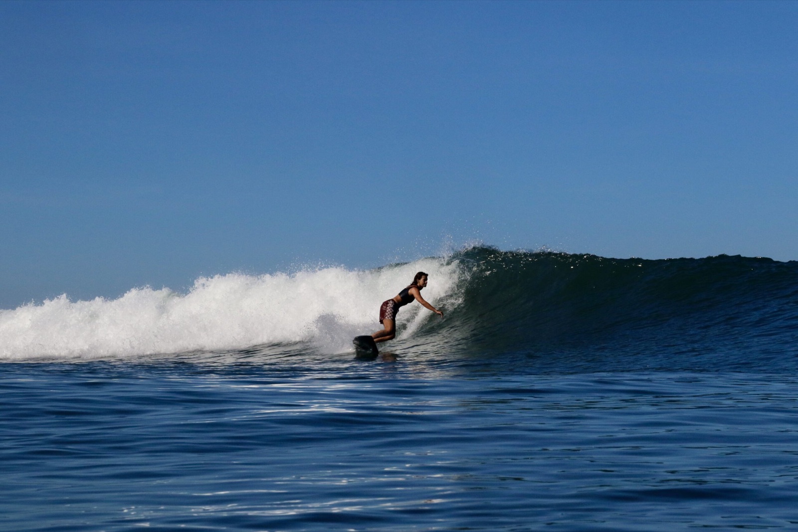 Surfer riding the open face of a long left at Medewi